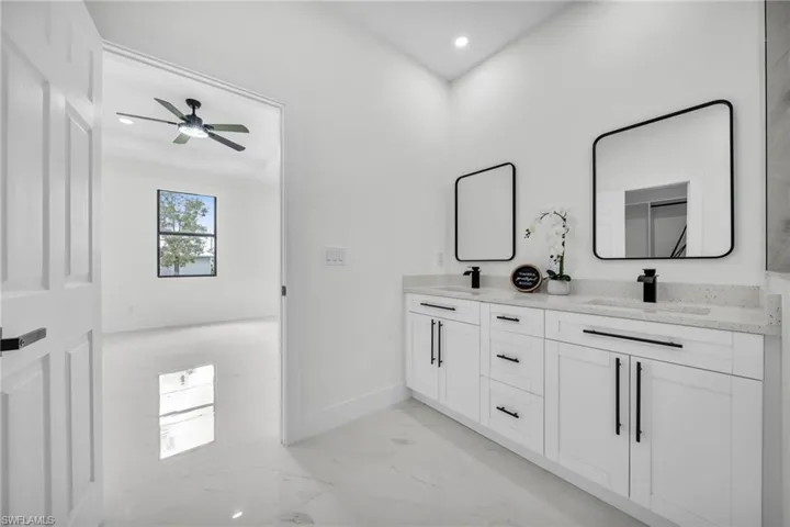 Full bath with double vanity, light marble finish flooring, recessed lighting, and ceiling fan