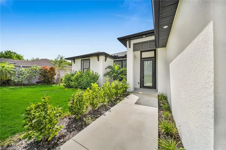 Property entrance with stucco siding and a yard