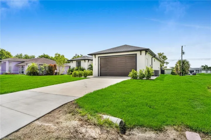 View of front of home with a front yard, driveway, and stucco siding