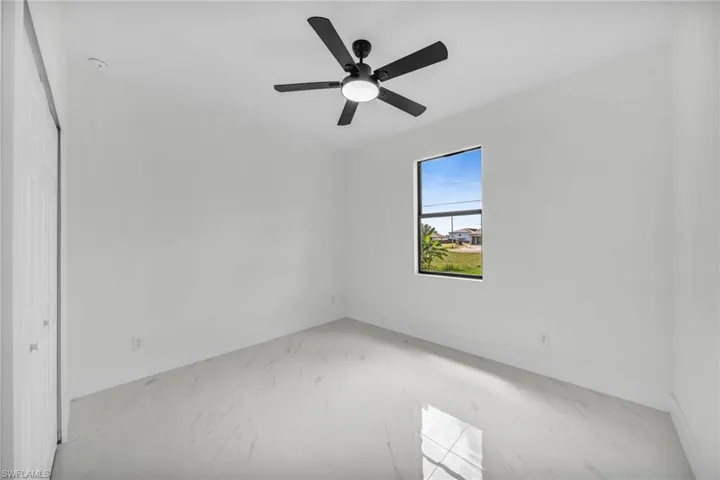 Empty room featuring light marble finish flooring and a ceiling fan