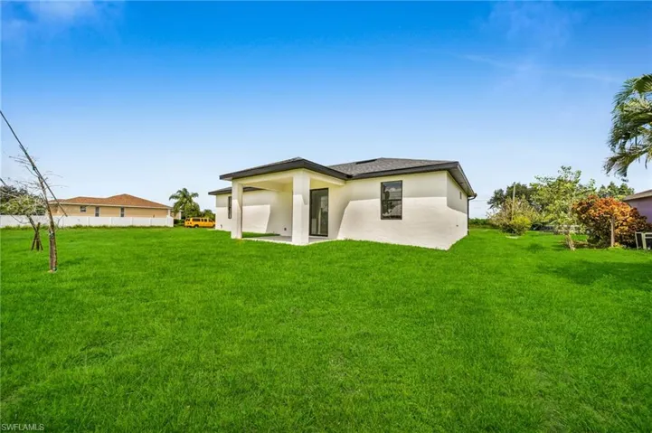 Rear view of house featuring a yard, a patio area, and stucco siding