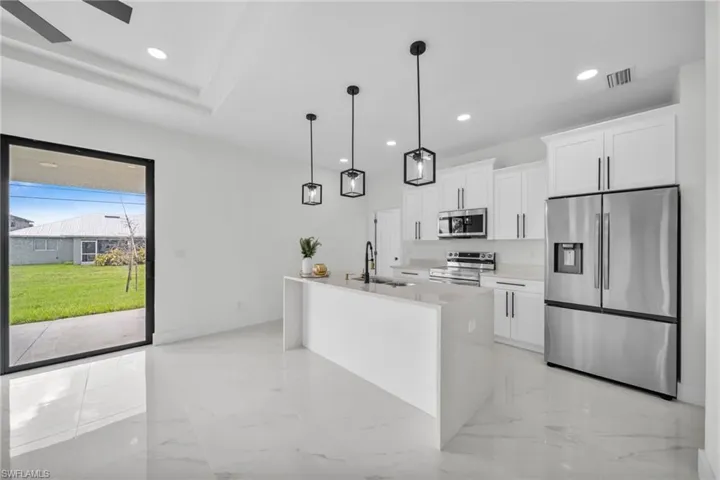 Kitchen with appliances with stainless steel finishes, light marble finish flooring, decorative light fixtures, white cabinets, and recessed lighting