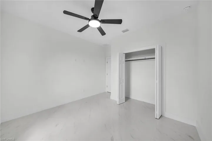 Unfurnished bedroom with light marble finish flooring, ceiling fan, and a closet