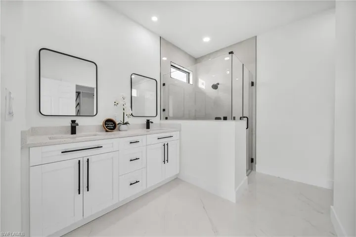 Full bathroom featuring light marble finish flooring, a marble finish shower, double vanity, and recessed lighting