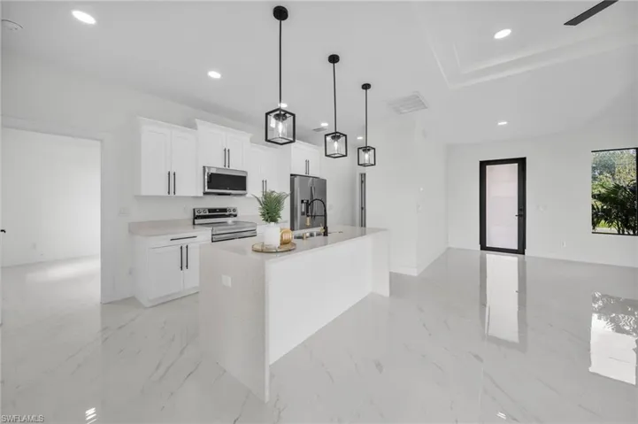 Kitchen featuring white cabinetry, appliances with stainless steel finishes, hanging light fixtures, a kitchen island with sink, and recessed lighting