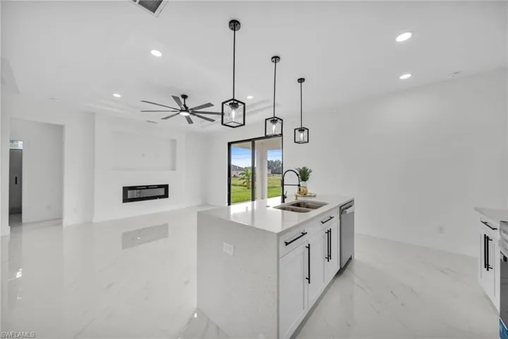 Kitchen with white cabinetry, light marble finish floors, decorative light fixtures, light stone countertops, and ceiling fan