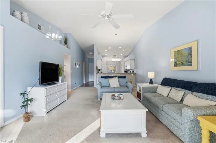 Living area featuring a chandelier, carpet flooring, a ceiling fan, lofted ceiling, and recessed lighting