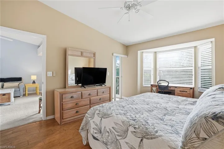 Bedroom featuring vaulted ceiling, light wood-style flooring, a ceiling fan, and access to exterior