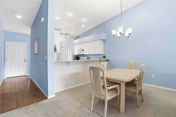 Dining area with a chandelier, light carpet, lofted ceiling, recessed lighting, and ceiling fan
