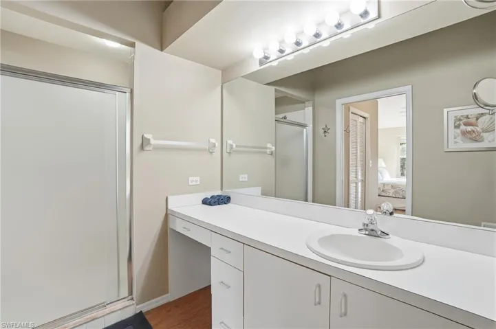 Ensuite bathroom with a stall shower, vanity, and dark wood-style flooring