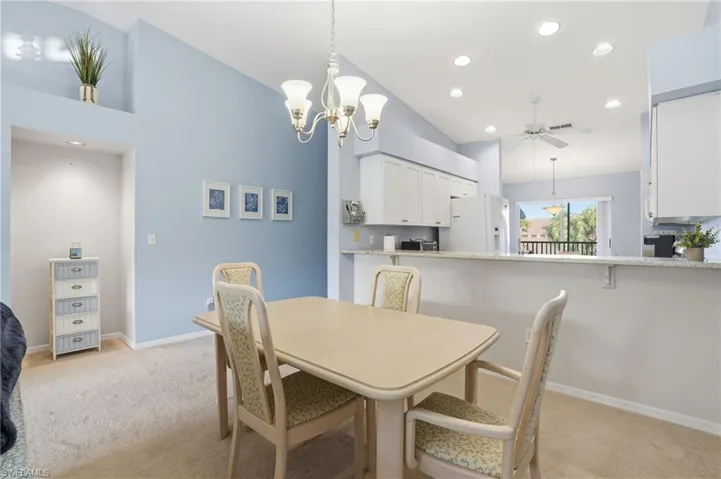 Dining room with a chandelier, light carpet, recessed lighting, ceiling fan, and high vaulted ceiling