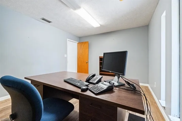Office area with light wood-type flooring and a textured ceiling