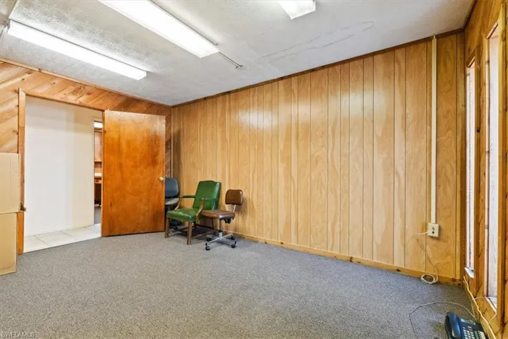 Unfurnished room featuring carpet flooring and wooden walls