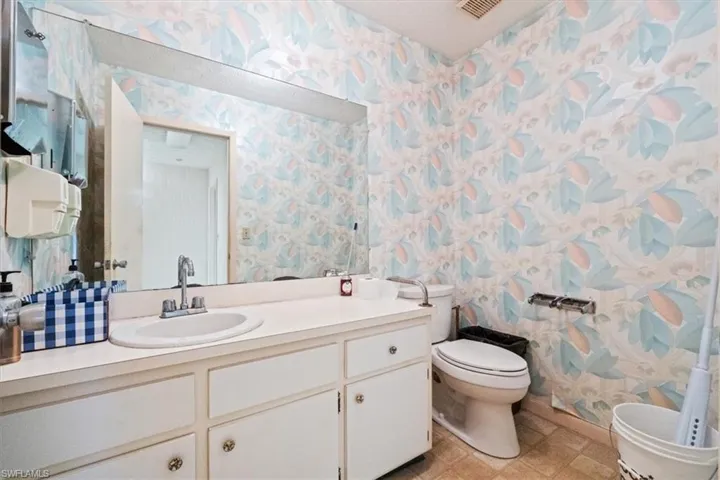 Bathroom featuring wallpapered walls and vanity
