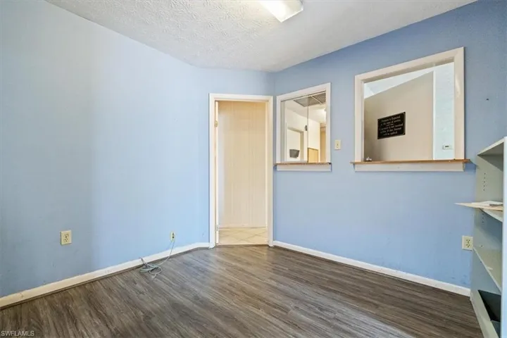 Spare room featuring dark wood-type flooring and a textured ceiling