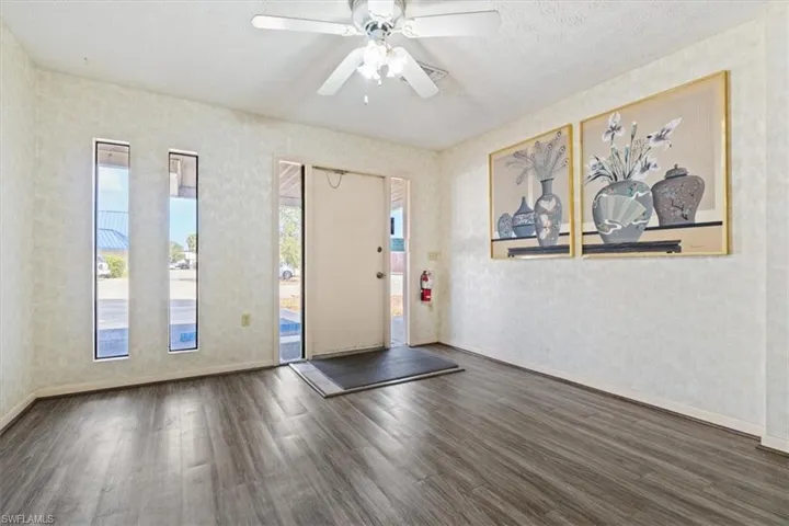Entrance foyer with a ceiling fan, dark wood-type flooring, a textured ceiling, and wallpapered walls