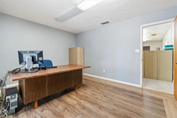 Office space with light wood-style flooring and a textured ceiling