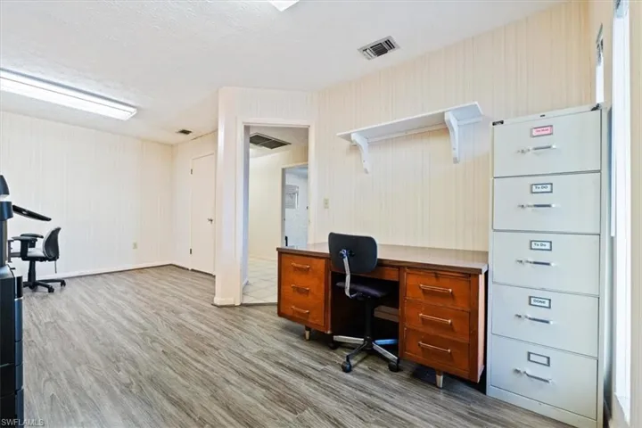 Office space featuring light wood-type flooring and a textured ceiling