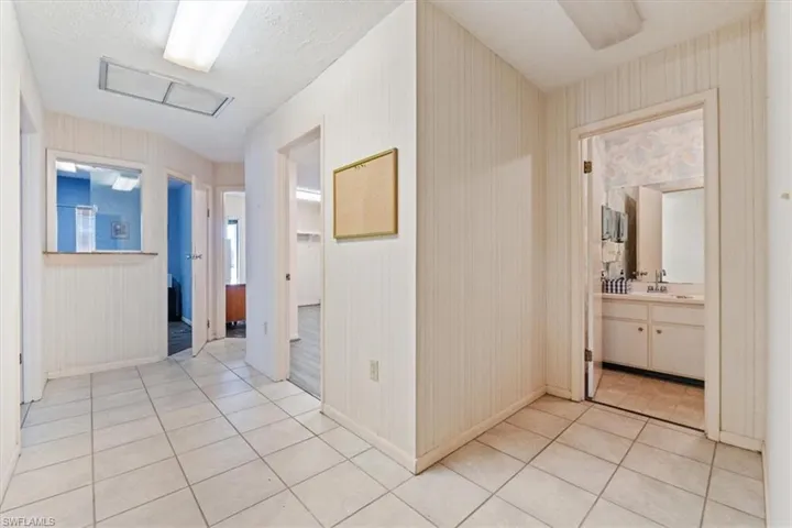 Hall featuring light tile patterned floors and a textured ceiling