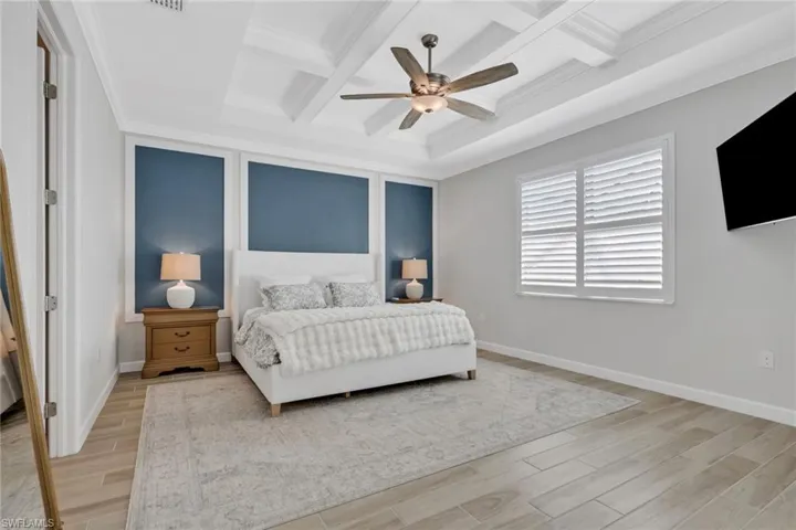 Bedroom featuring coffered ceiling, light wood-style flooring, ceiling fan, beam ceiling, and crown molding