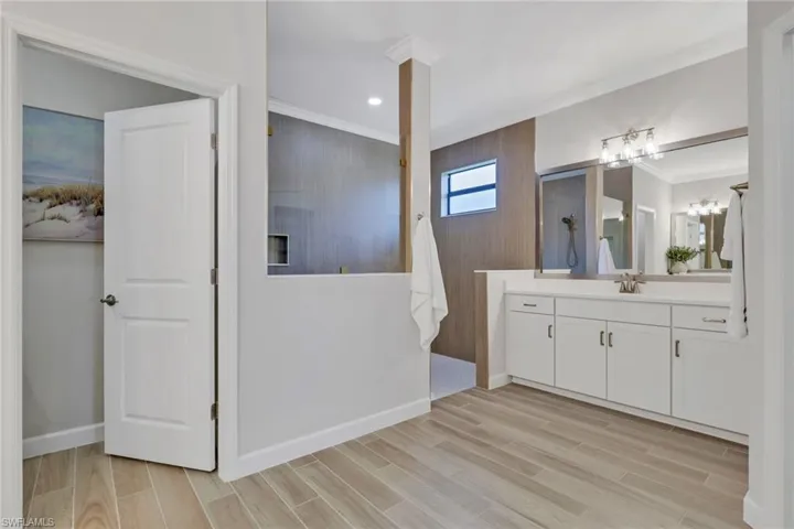 Full bath featuring vanity, wood tiled floors, crown molding, recessed lighting, and walk in shower