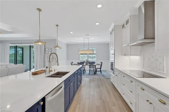 Kitchen featuring white cabinetry, blue cabinets, decorative light fixtures, wall chimney exhaust hood, and recessed lighting