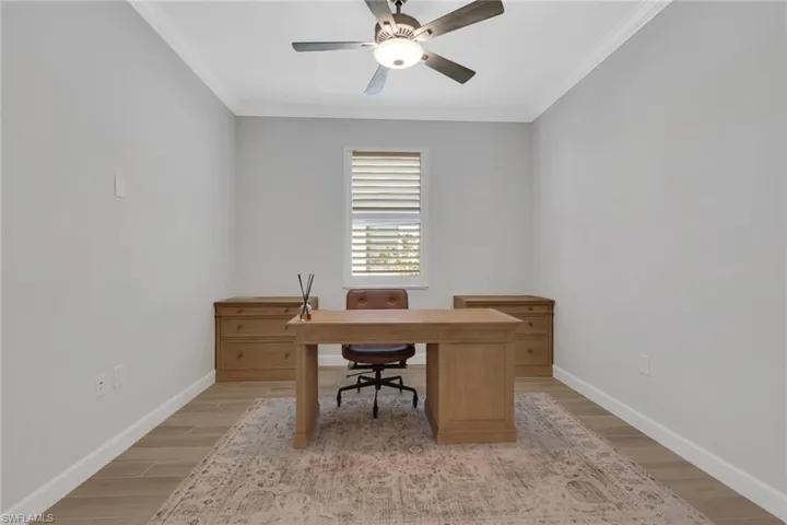 Office space with light wood-type flooring, crown molding, and ceiling fan