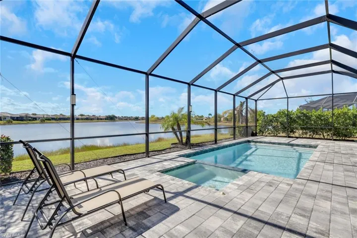 View of pool featuring a sunroom, a pool with connected hot tub, a water view, a lanai, and a patio