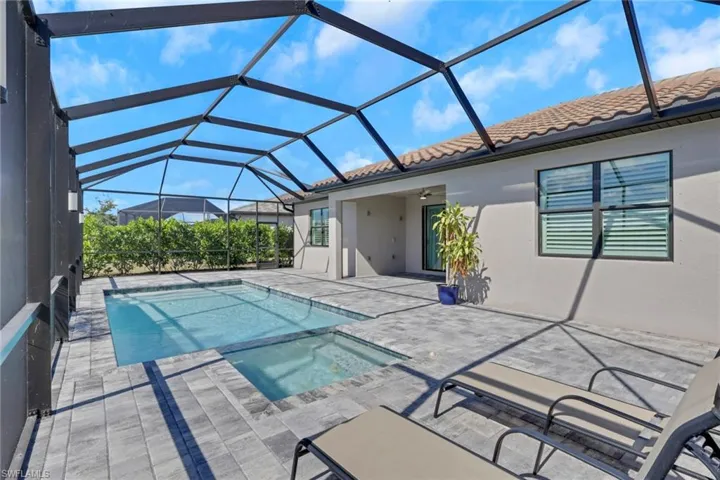 View of pool featuring a sunroom, a patio area, glass enclosure, and a pool with connected hot tub