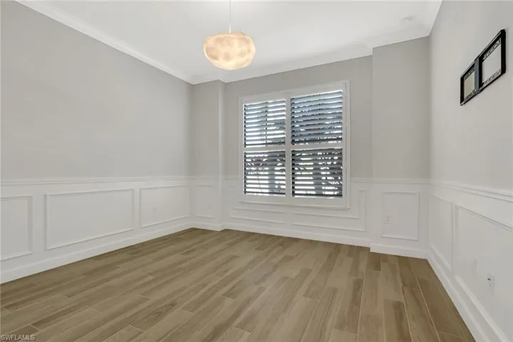 Spare room with ornamental molding, light wood-type flooring, wainscoting, and a decorative wall