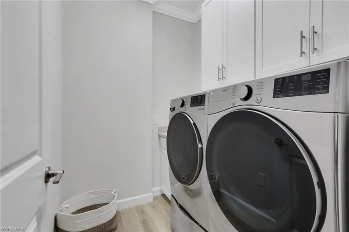 Washroom with wood finish floors, cabinet space, independent washer and dryer, and ornamental molding