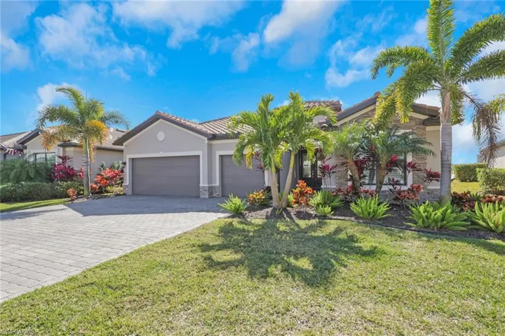 Mediterranean / spanish-style home featuring stone siding, stucco siding, a garage, decorative driveway, and a front lawn