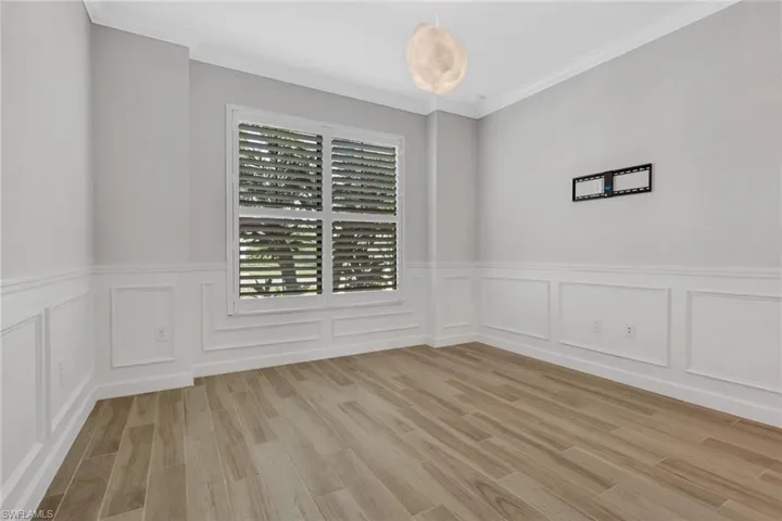 Unfurnished room featuring ornamental molding, light wood-style floors, a wainscoted wall, and a decorative wall