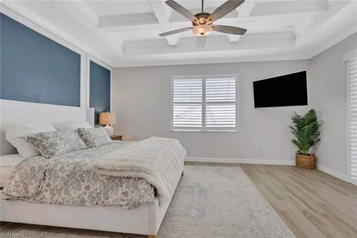 Bedroom with coffered ceiling, light wood-style floors, beamed ceiling, a ceiling fan, and ornamental molding