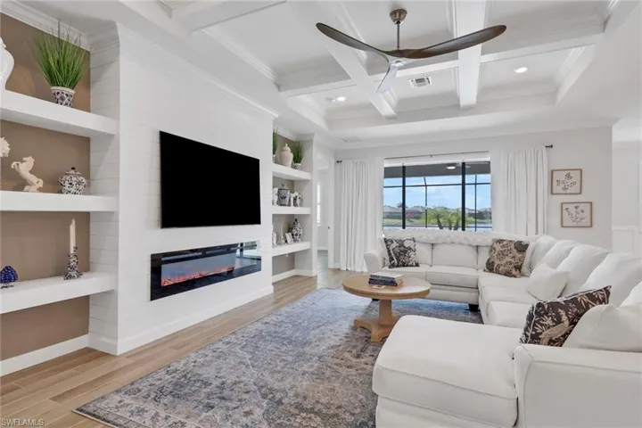 Living room with built in shelves, a fireplace, coffered ceiling, light wood-type flooring, and a ceiling fan