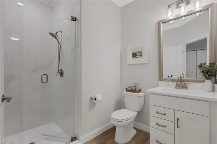 Full bathroom with vanity, a marble finish shower, and wood tiled floors