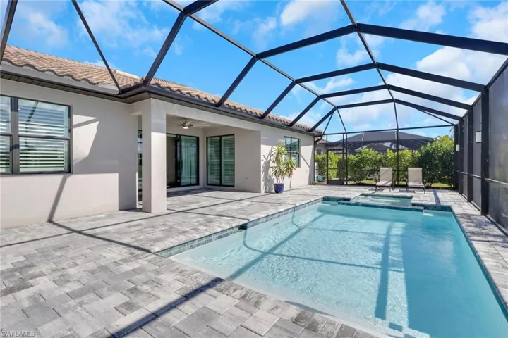 View of swimming pool featuring a sunroom, a patio, glass enclosure, and a pool with connected hot tub