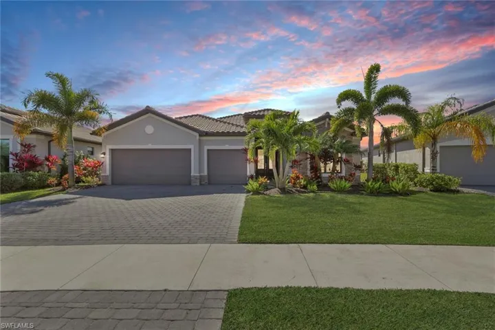 View of front of house with a front yard, a garage, decorative driveway, stucco siding, and stone siding