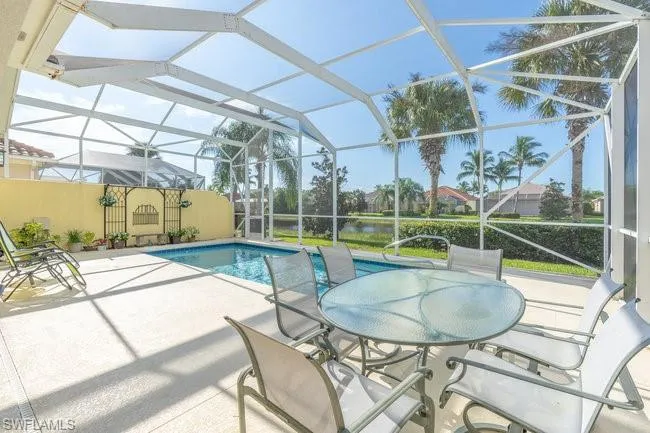 View of pool featuring glass enclosure and a patio area