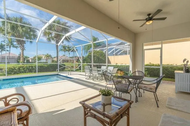 View of pool featuring a patio, glass enclosure, and ceiling fan