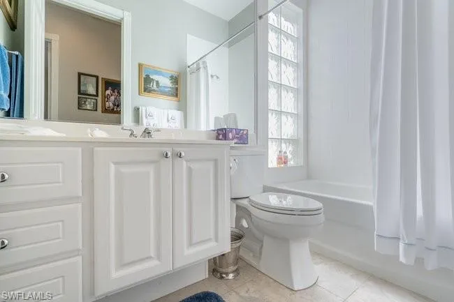 Full bathroom featuring shower / tub combo with curtain, tile patterned floors, vanity, and toilet