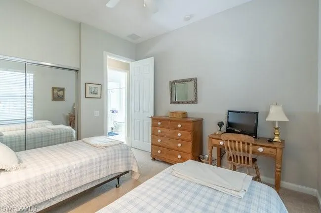 Bedroom with a closet, ceiling fan, and light colored carpet