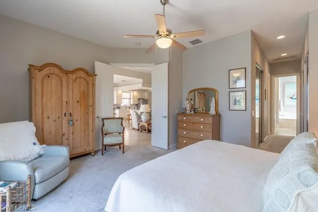 Carpeted bedroom with ceiling fan and connected bathroom