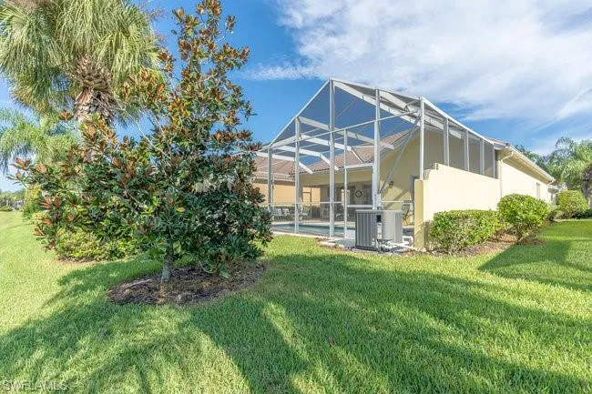 Rear view of house featuring glass enclosure, a yard, and central AC unit