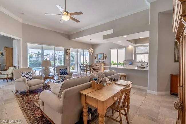 Tiled living room featuring sink, ceiling fan with notable chandelier, and ornamental molding