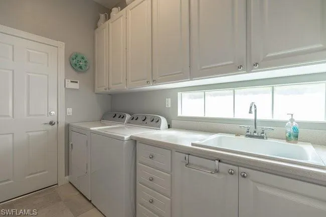Laundry room with cabinets, sink, independent washer and dryer, and a wealth of natural light