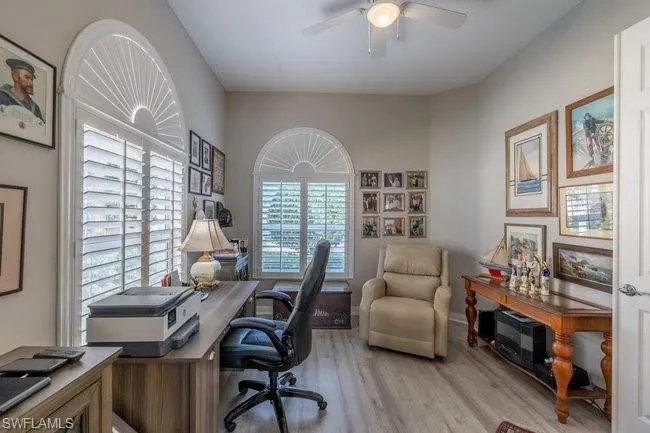 Office area with light wood-type flooring, a healthy amount of sunlight, and ceiling fan
