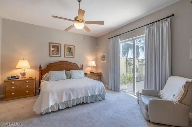 Bedroom with ceiling fan, light colored carpet, and access to exterior