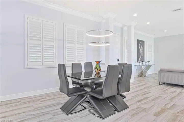 Dining area with a notable chandelier, light hardwood / wood-style flooring, and crown molding