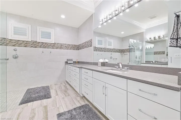 Bathroom with tile walls, crown molding, vanity, and tiled shower